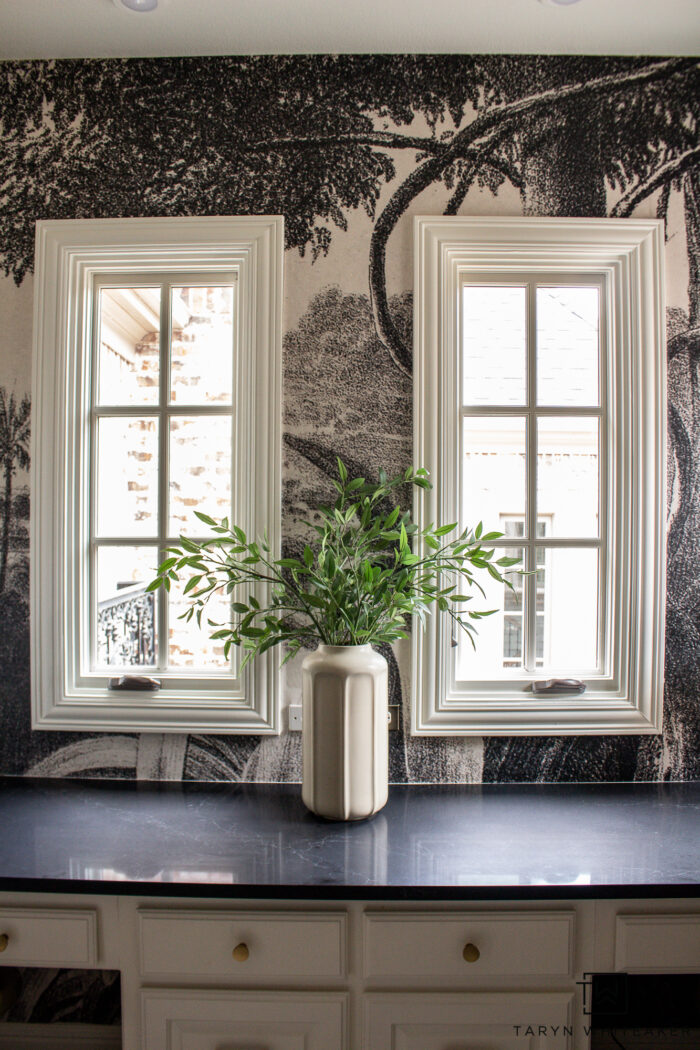 Tour this whimsical black and cream study design with a vintage wall mural black quartz countertops, modern globe chandelier and brass accents