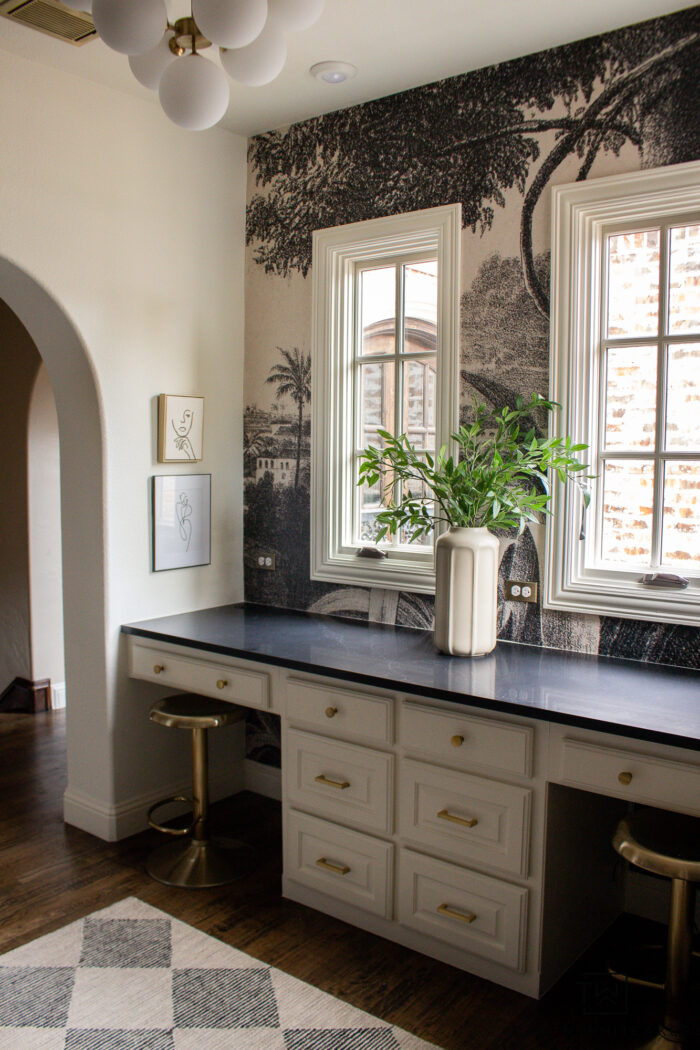 Tour this whimsical black and cream study design with a vintage wall mural black quartz countertops, modern globe chandelier and brass accents