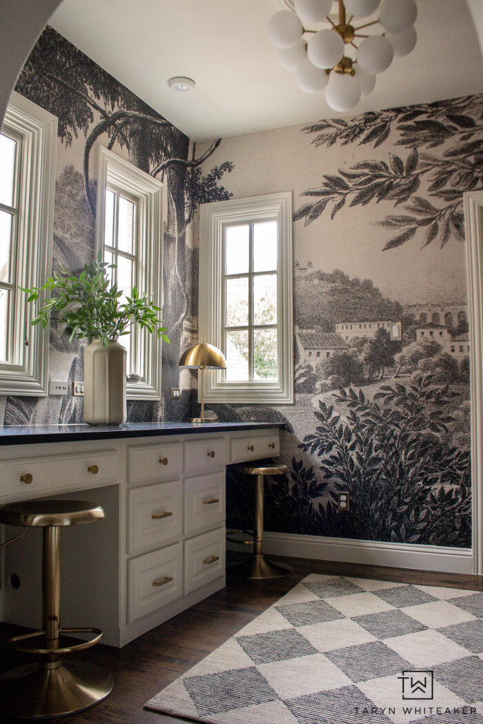 Tour this whimsical black and cream study design with a vintage wall mural black quartz countertops, modern globe chandelier and brass accents