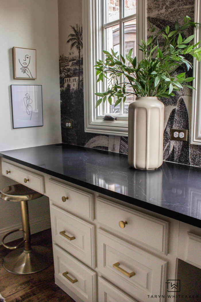 Tour this whimsical black and cream study design with a vintage wall mural black quartz countertops, modern globe chandelier and brass accents