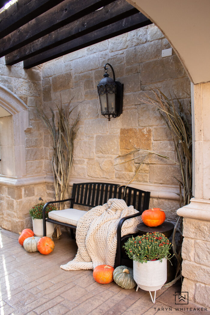 Cozy fall bench display with cozy blanket, corn stalks, heirloom pumpkins and mums. The perfect simple fall entry display. 