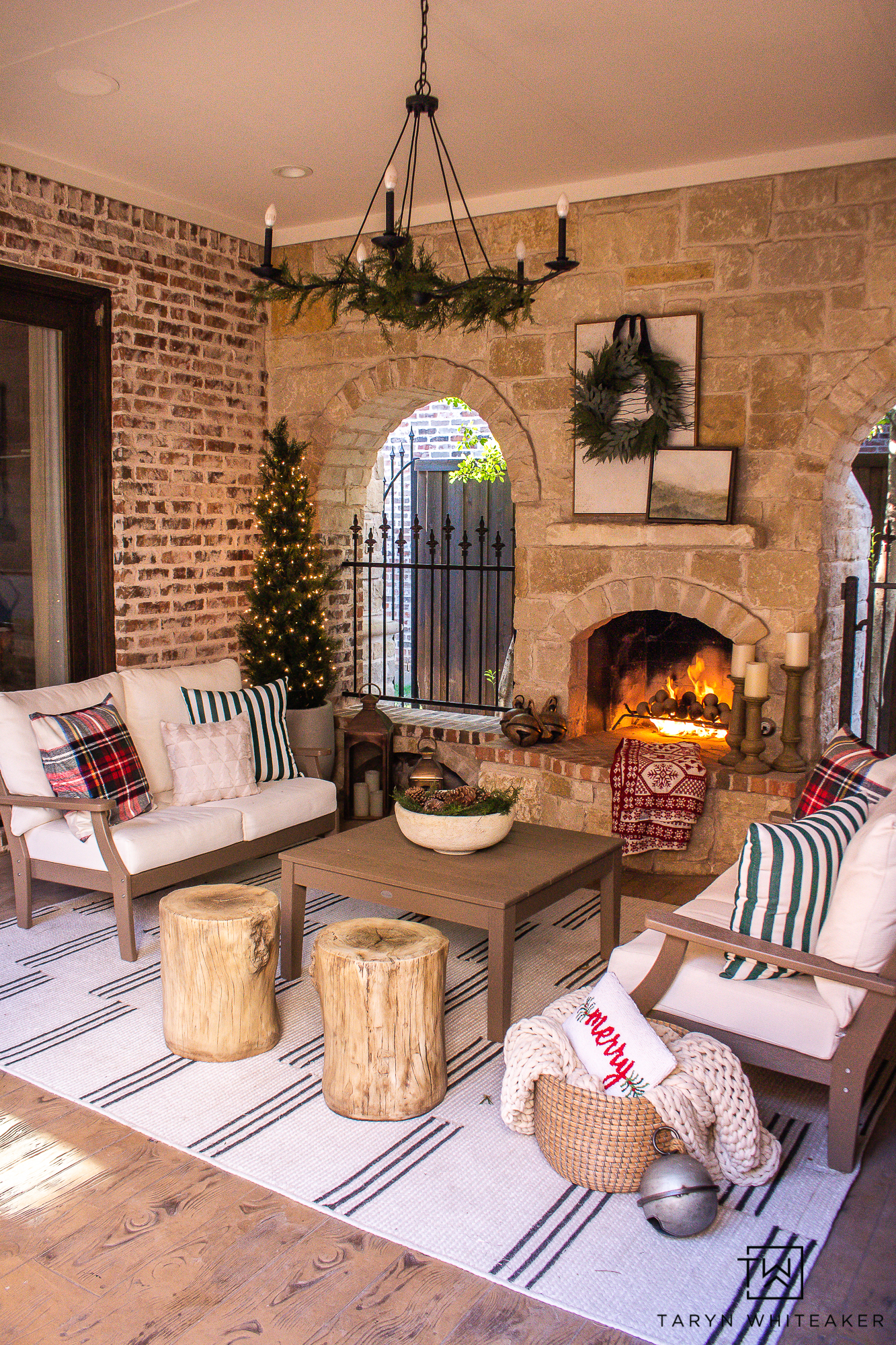 Tips For Decorating an outdoor fireplace for Christmas with pops of plaid and olive green and adorned with realistic garland and lit trees. 