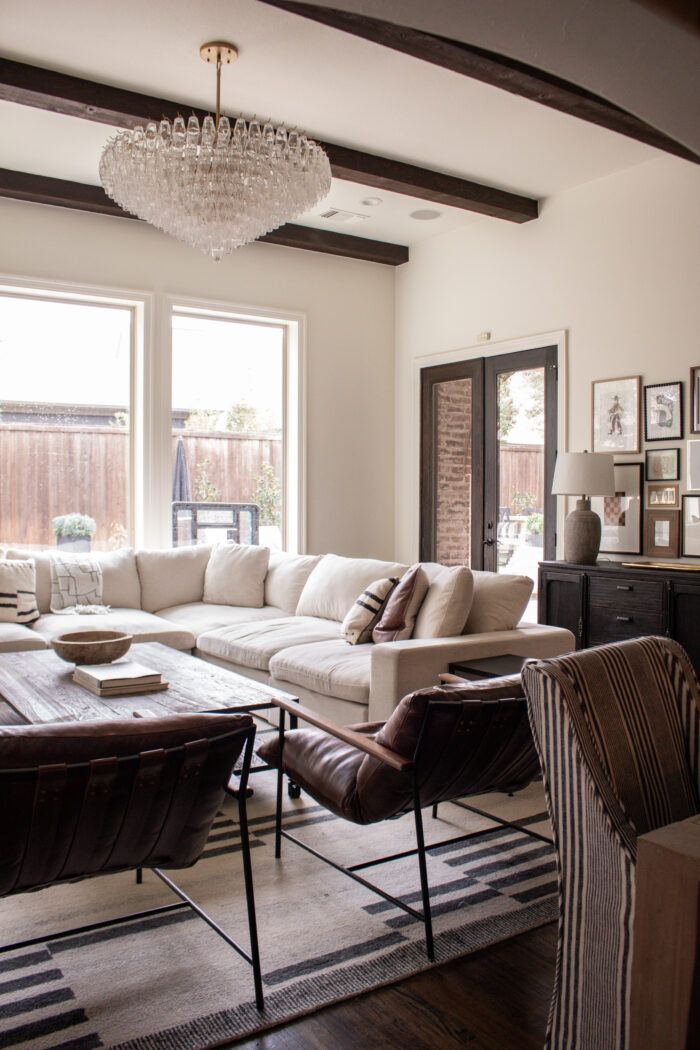 Neutral Modern Transitional Family Room Decor with glass statement chandelier, large corner sectional, modern home accents.
